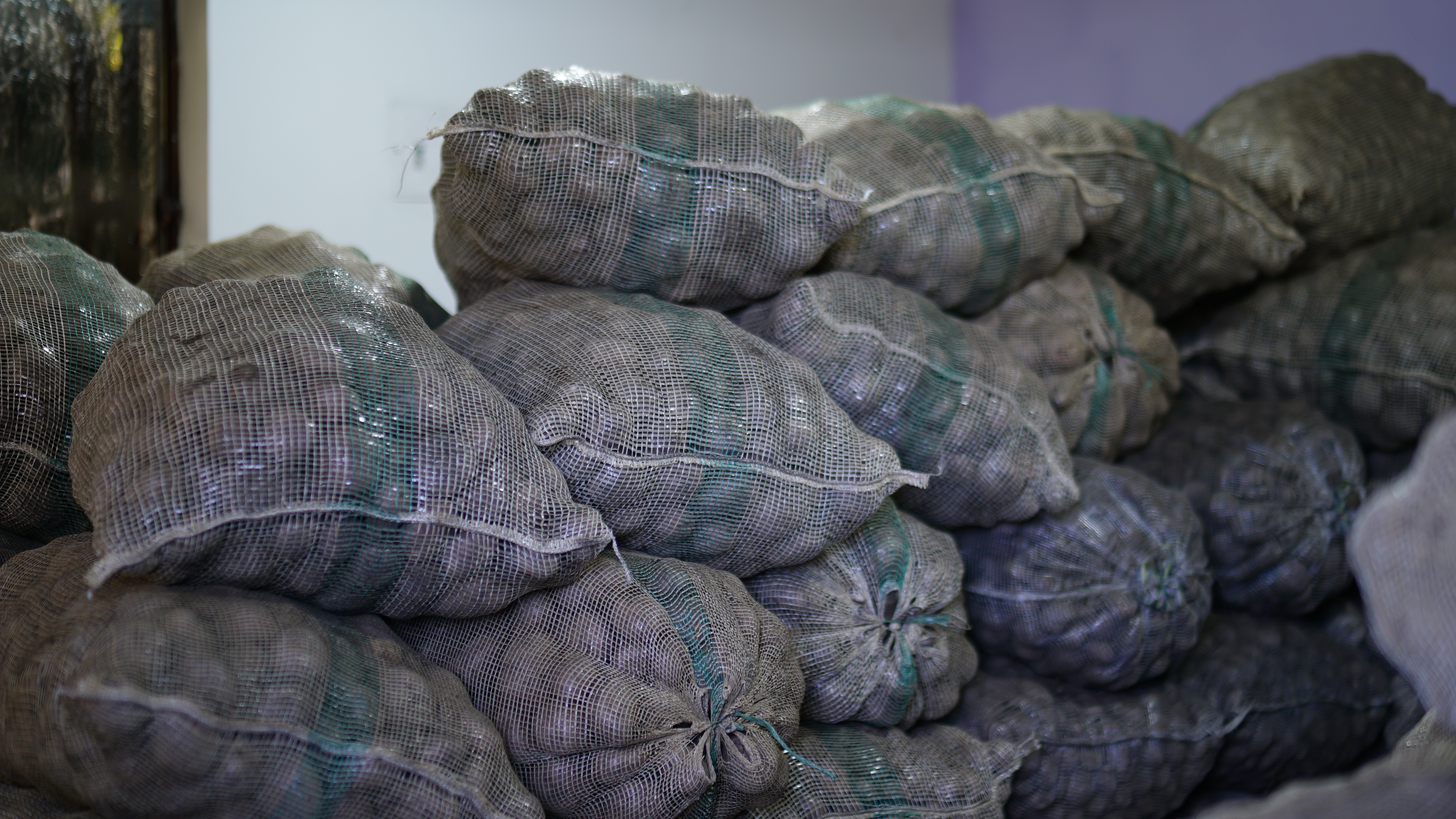 Fotografías de varios bultos de papa depositados en un recinto con poca luz