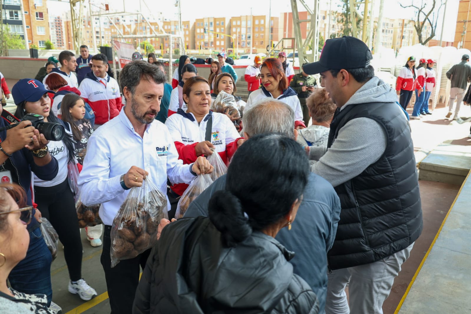 fotografía en la que aparecen el director de la región metropolitana y el alcalde Soacha entregando papa a habitantes de ese municipio