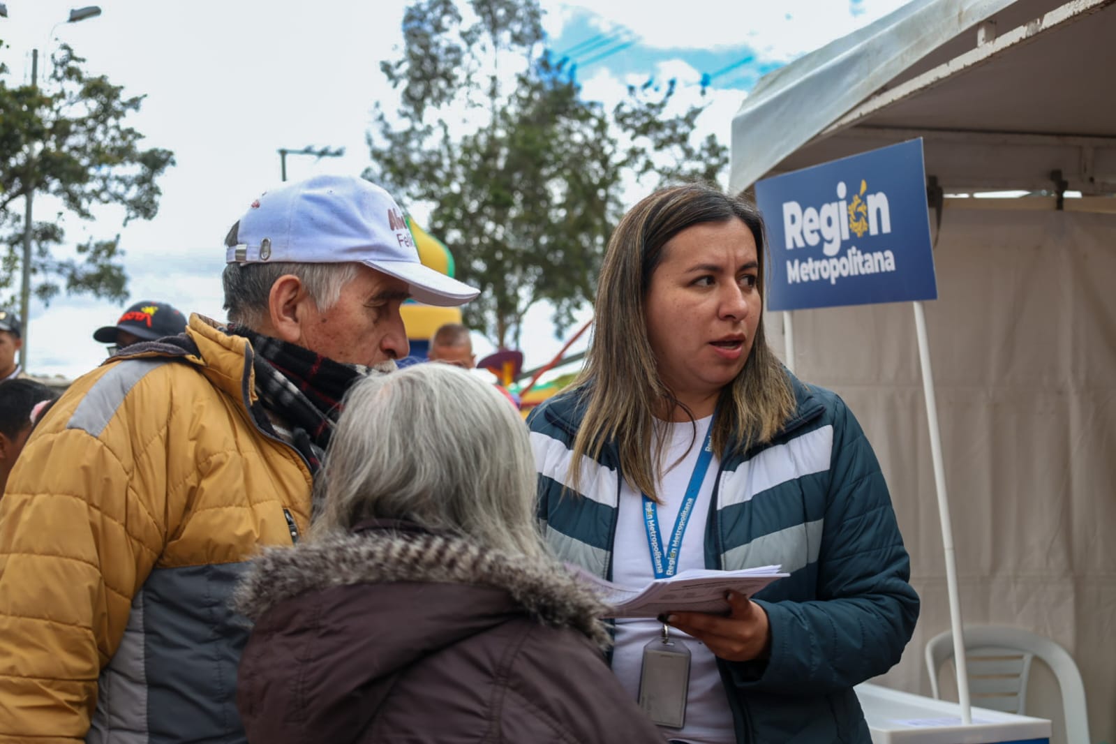 Fotografía de una funcionaria de la región metropolitana atendiendo a una ciudadana alrededor de una carpa instalada en la jornada de atención a la ciudadanía en el borde Bogotá - Soacha