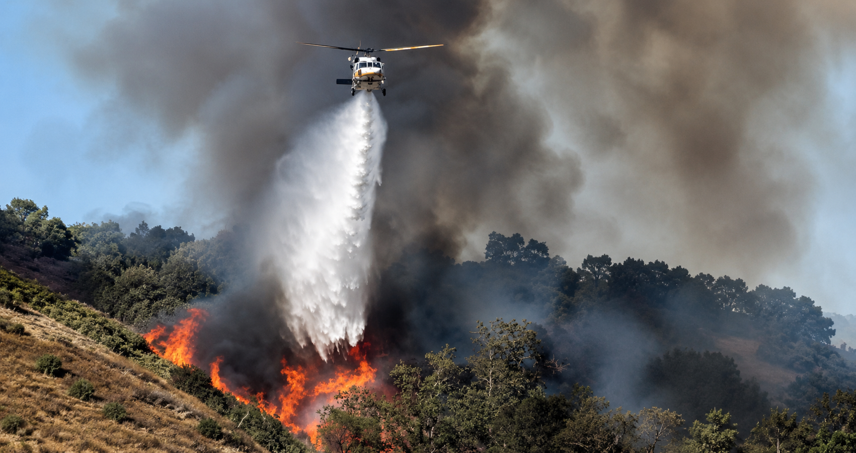 Imagen de un incendio forestal y un helicóptero en labores de atención de emergencias