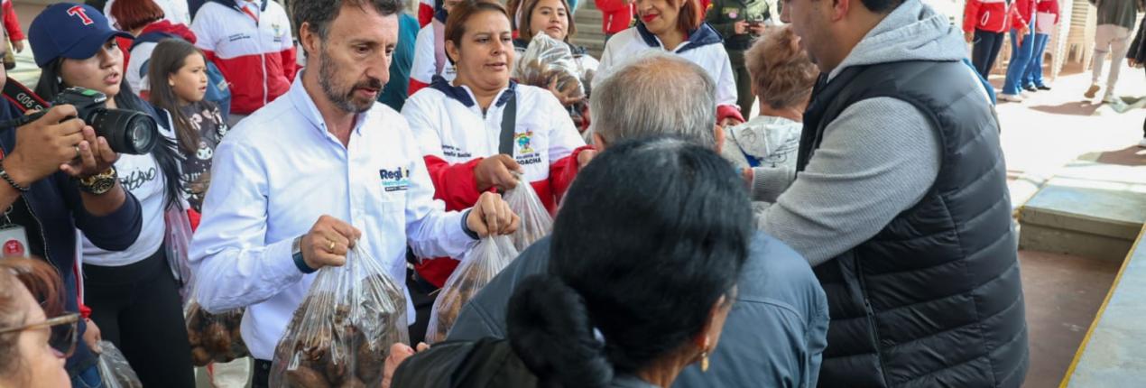 fotografía en la que aparecen el director de la región metropolitana y el alcalde Soacha entregando papa a habitantes de ese municipio