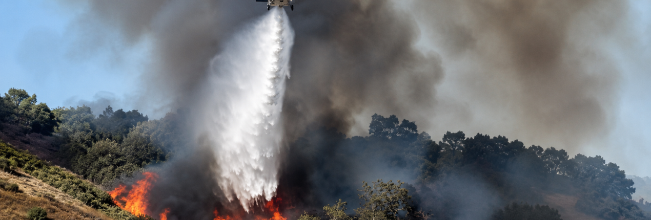 Imagen de un incendio forestal y un helicóptero en labores de atención de emergencias