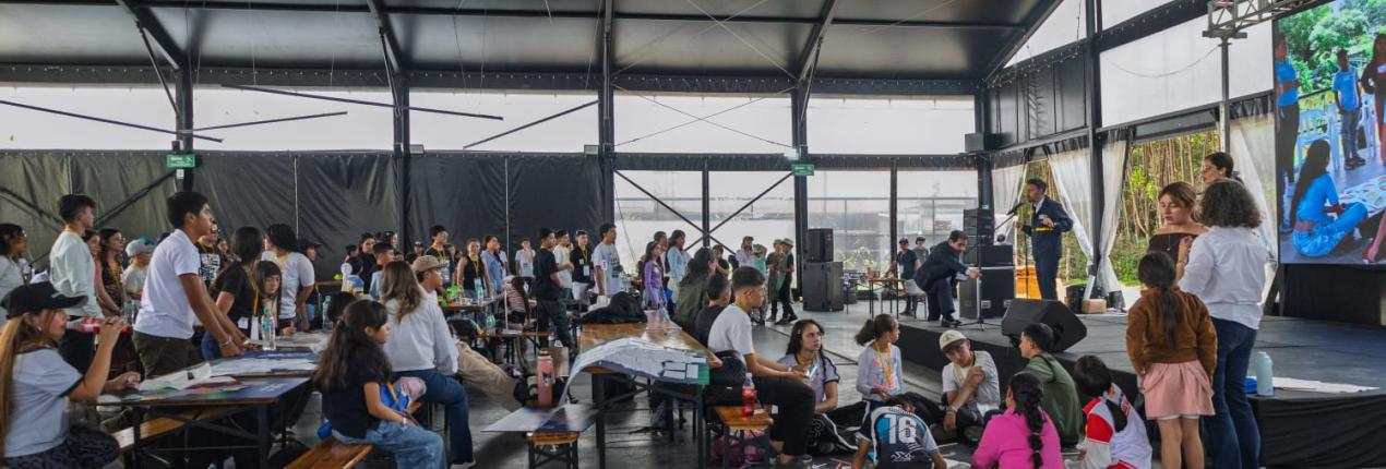 Fotografía de varios niños, niñas y adolescentes al interior de una carpa grande en la que se desarrolla una actividad lúdica