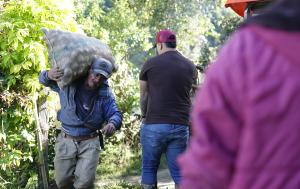 Fotografía muestra a campesino con un bulto de papa al hombre mientras se desplaza por un camino en un ambiente rural o de campo