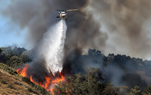 Imagen de un incendio forestal y un helicóptero en labores de atención de emergencias