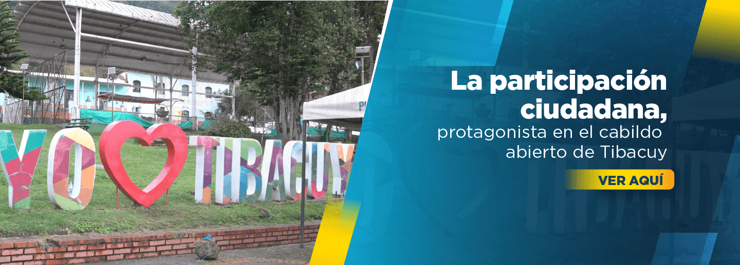 Banner muestra un aviso hecho en concreto que dice Yo amo a Tibacuy con un corazón y letras de colores sobre el césped