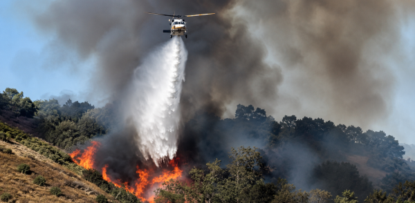 Imagen de un incendio forestal y un helicóptero en labores de atención de emergencias